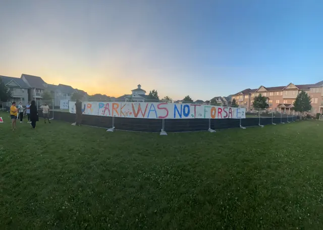 The finished banner on the construction fence at dusk.