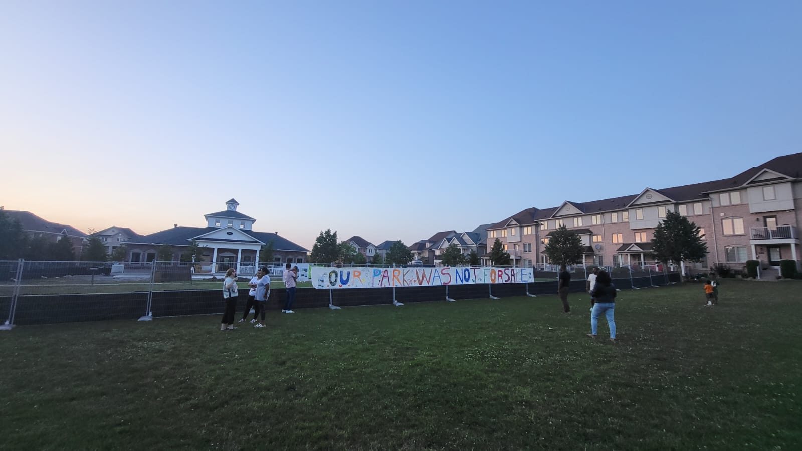 The banner hung across the fence, the Pavilion behind it.
